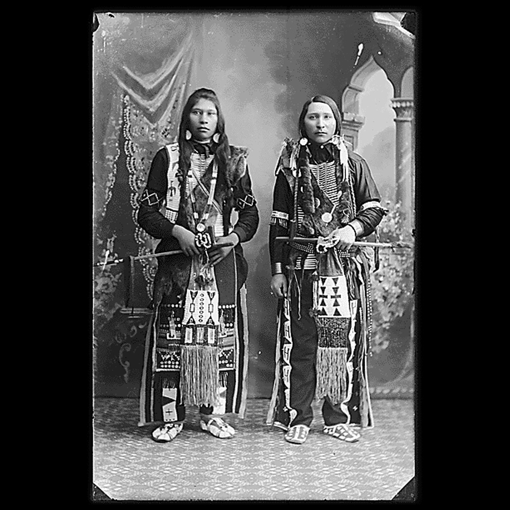 Photograph of two adult men from the Boise Valley Shoshone and Northern Shoshone tribes in traditional dress.