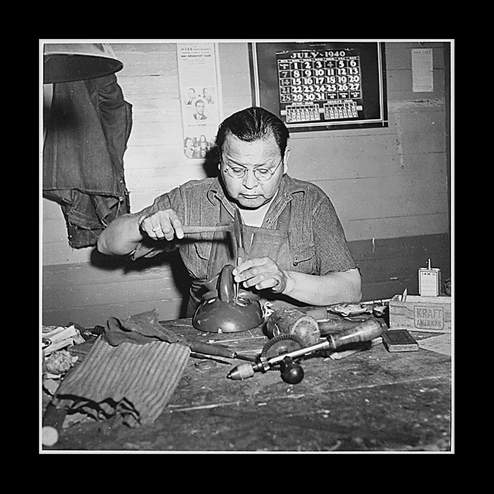 Photograph of Native American man carving a ceremonial mask.