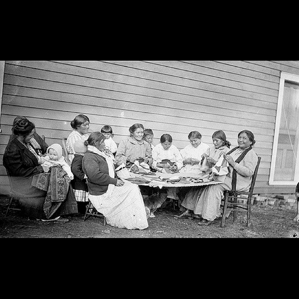 Native American women seated around a table sewing